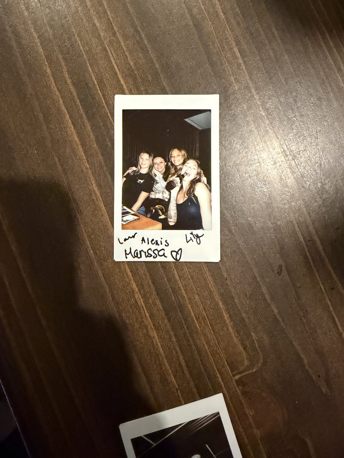 A polaroid photo of friends at karaoke, signed by the crew