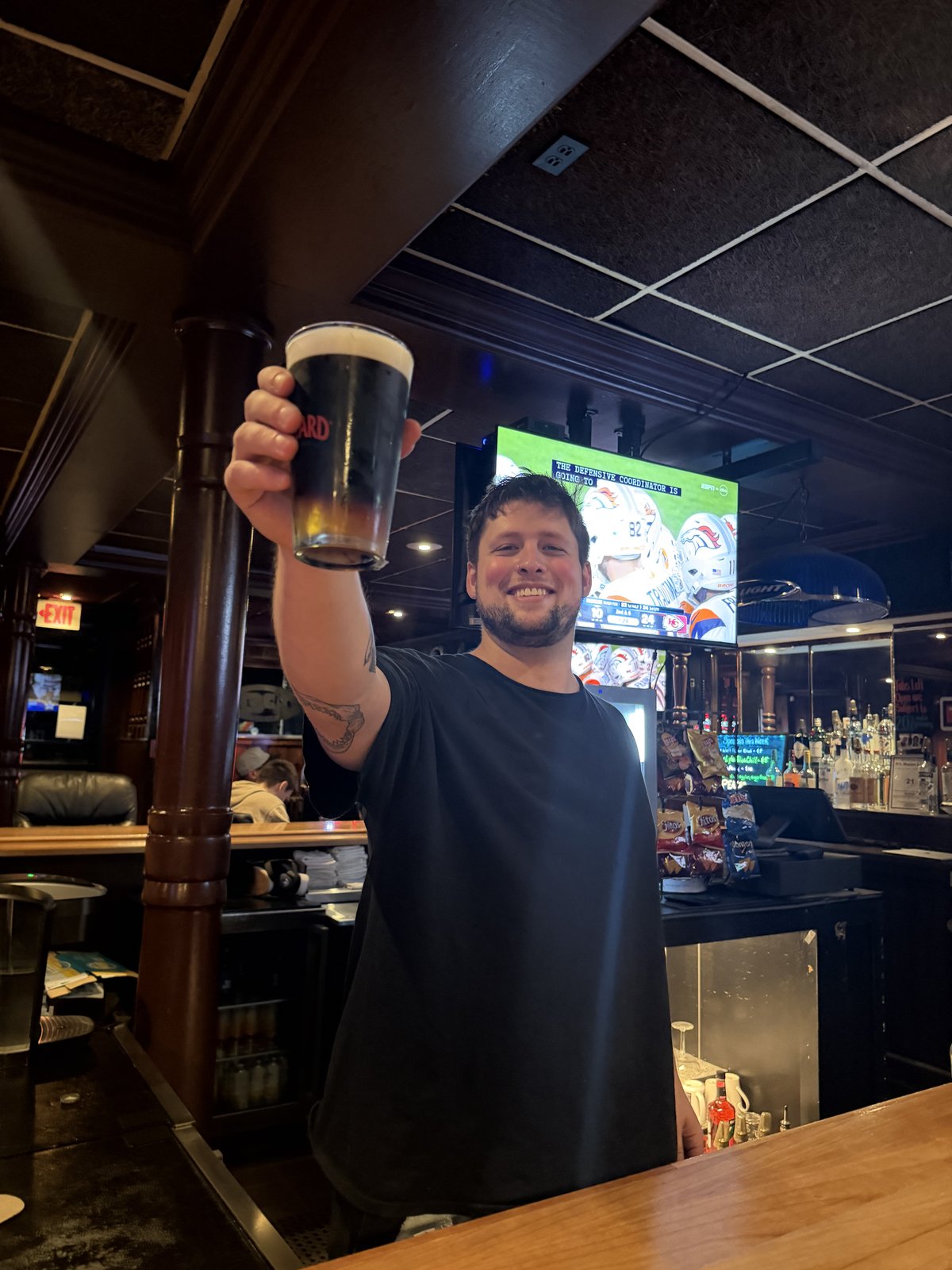 A bartender raising a stout behind the bar